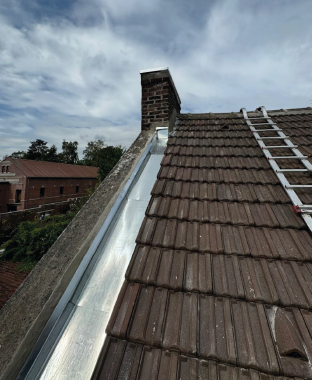 Toiture en tuiles avec ligne de faîtage en zinc